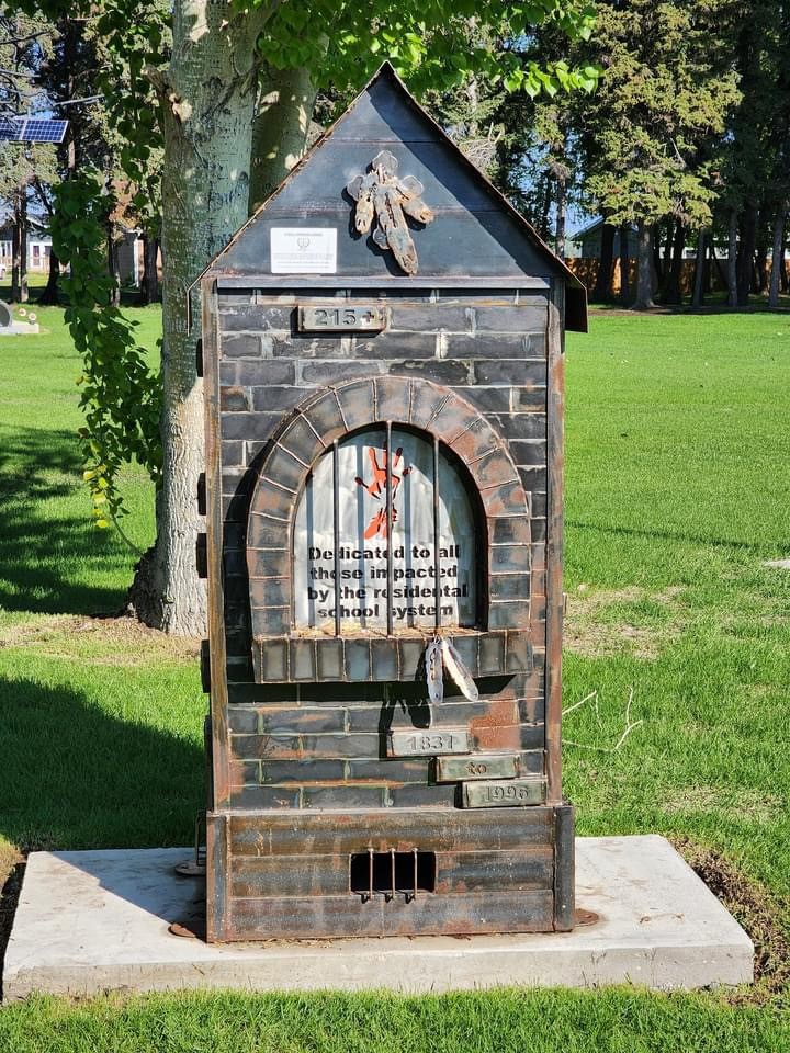 House-shaped metal memorial with the words “Dedicated to all those impacted by the residential school system” and the dates 1931 to 1996.